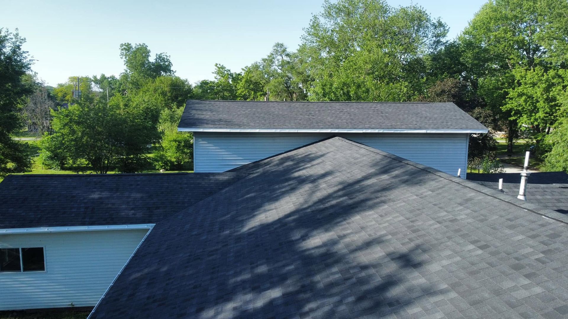 Roofs of suburban houses with trees in the background on a sunny day