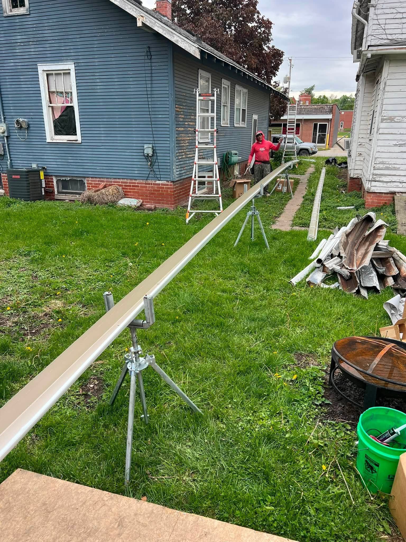 Backyard between blue and white houses with ladder, construction materials, and green grass