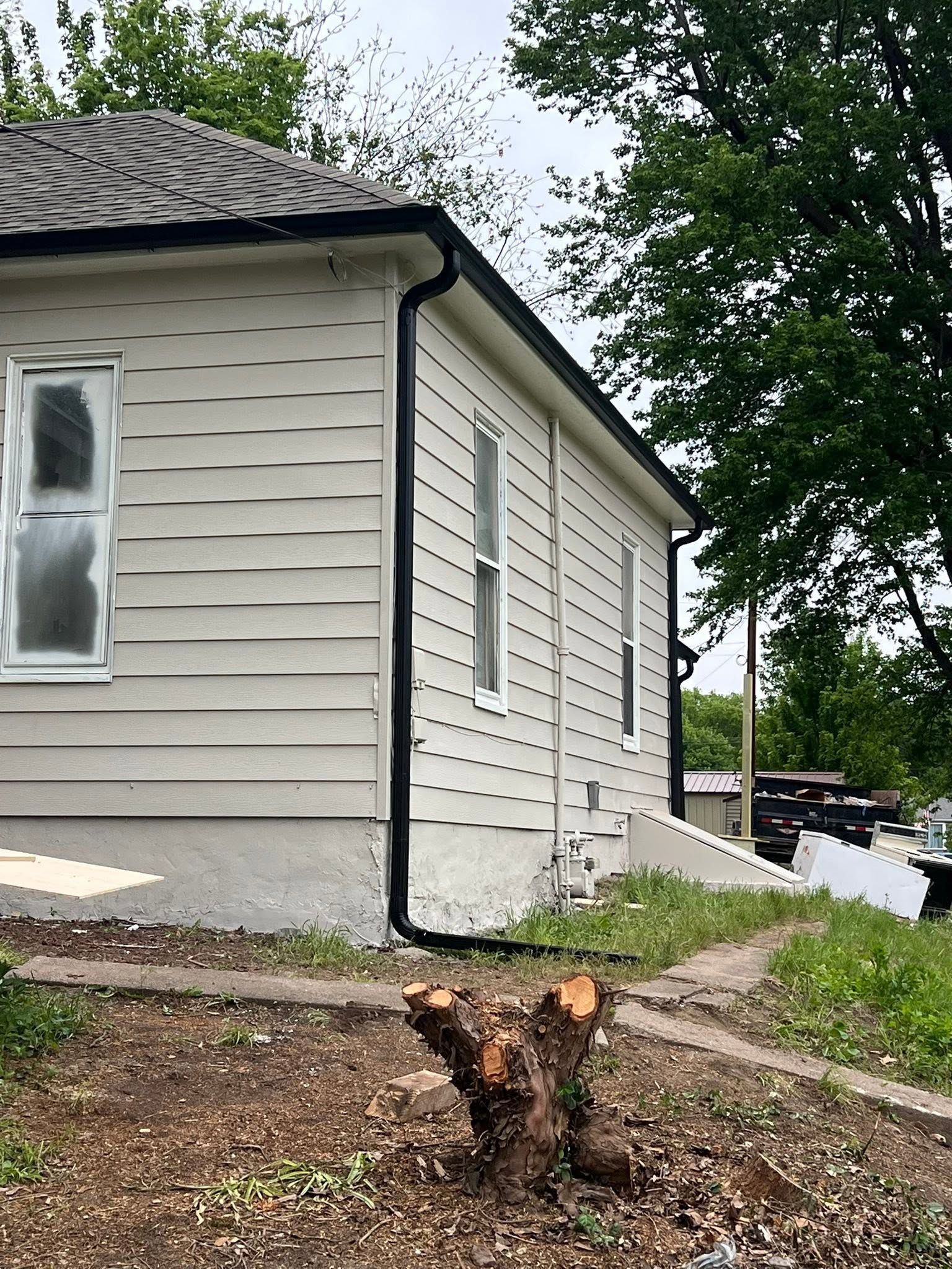House exterior with a freshly cut tree stump in the front yard and a driveway beside it