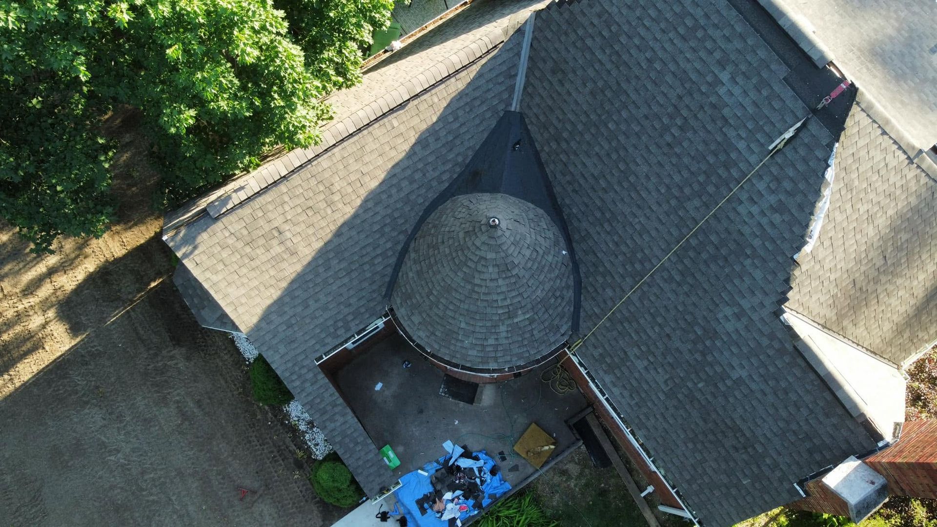 Aerial view of a gray-roofed building with a round turret and trees nearby