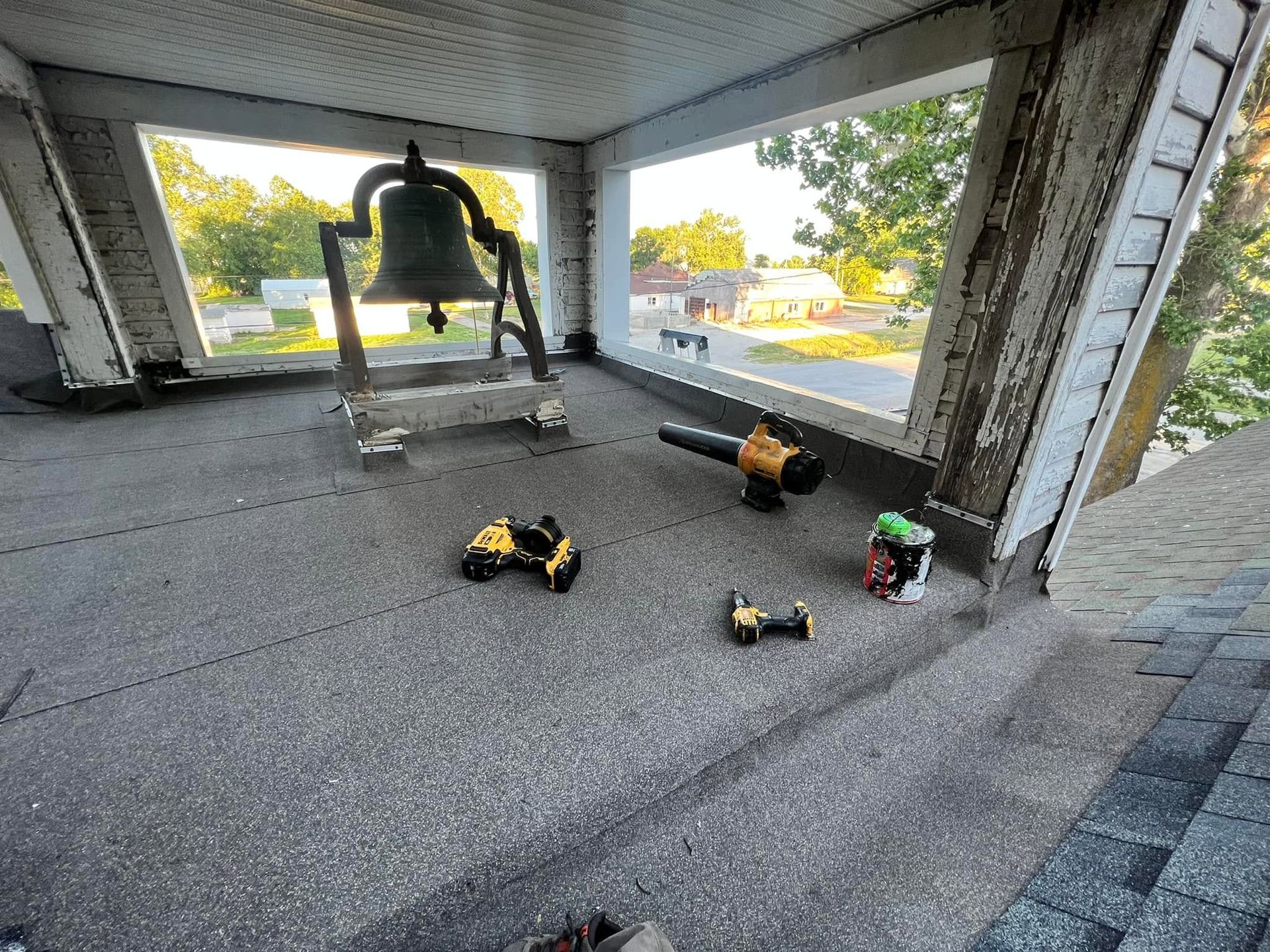 Bell tower interior with large hanging bell and several power tools on the floor.