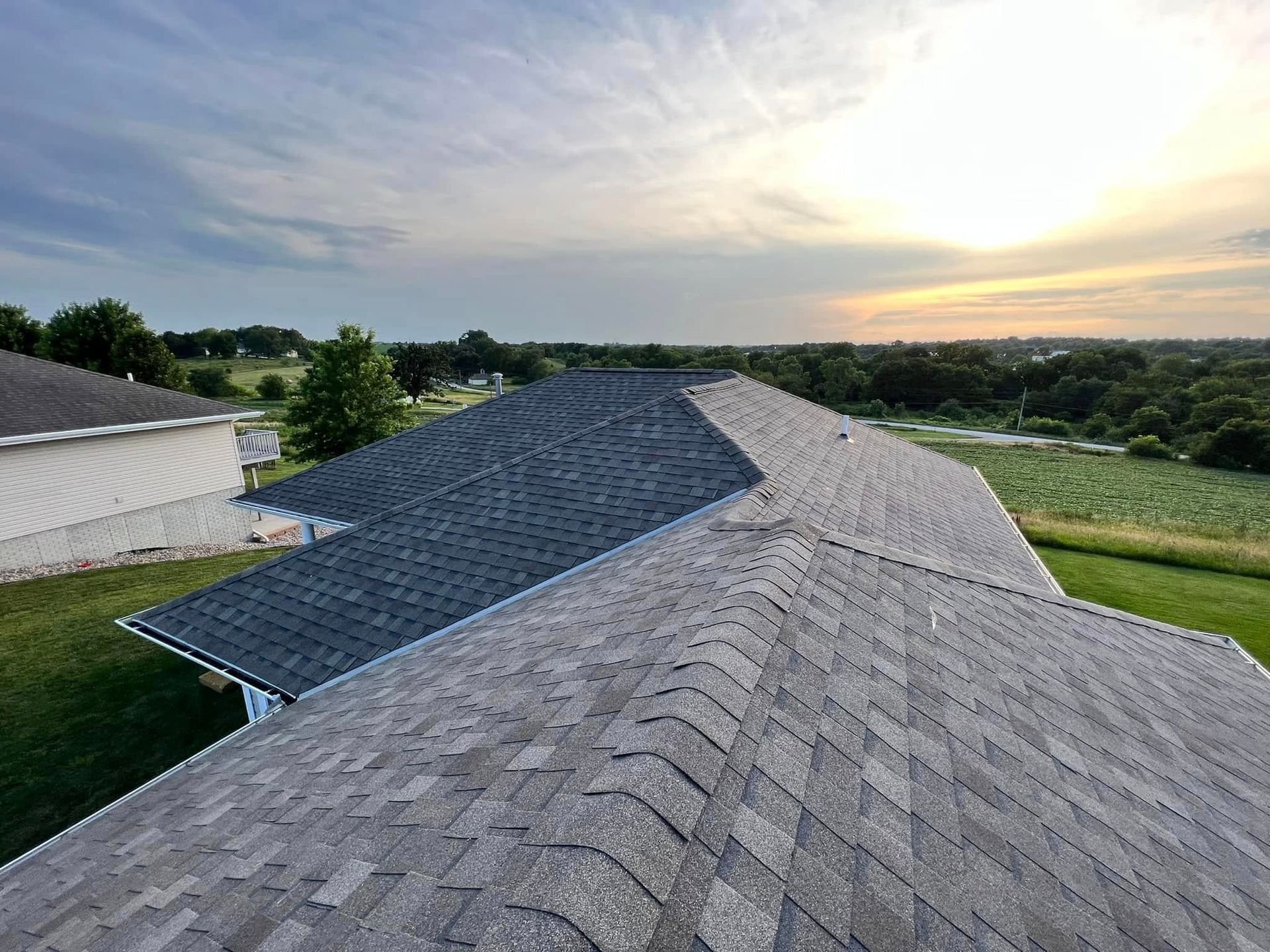 Roof shingles at sunset overlooking a green landscape