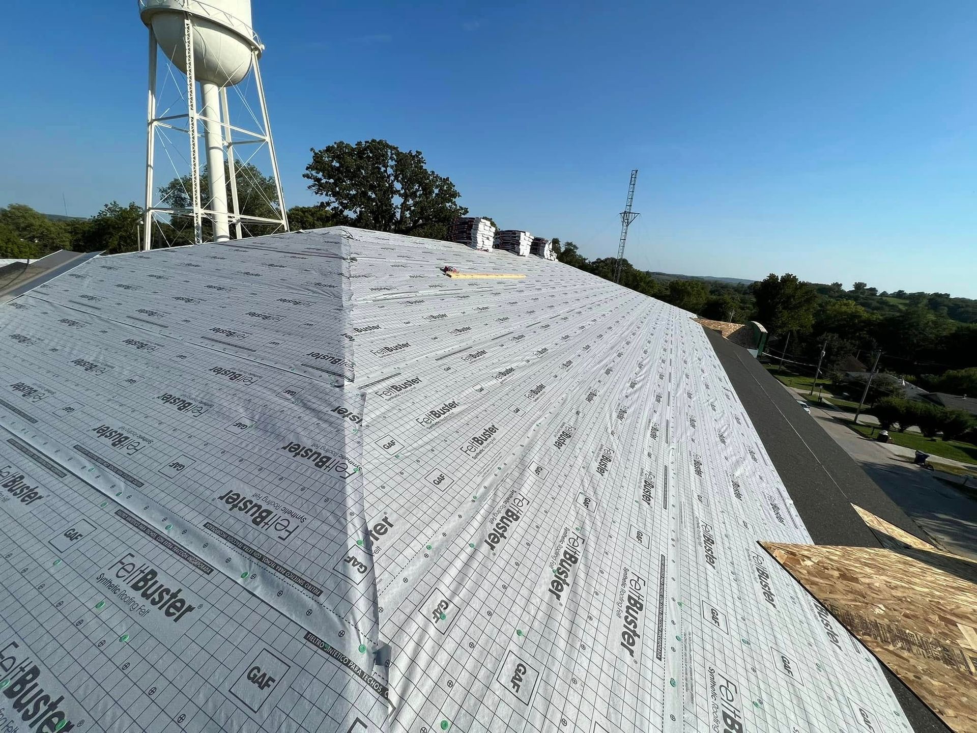 Rooftop covered in white weatherproof wrap beside a water tower on a sunny day
