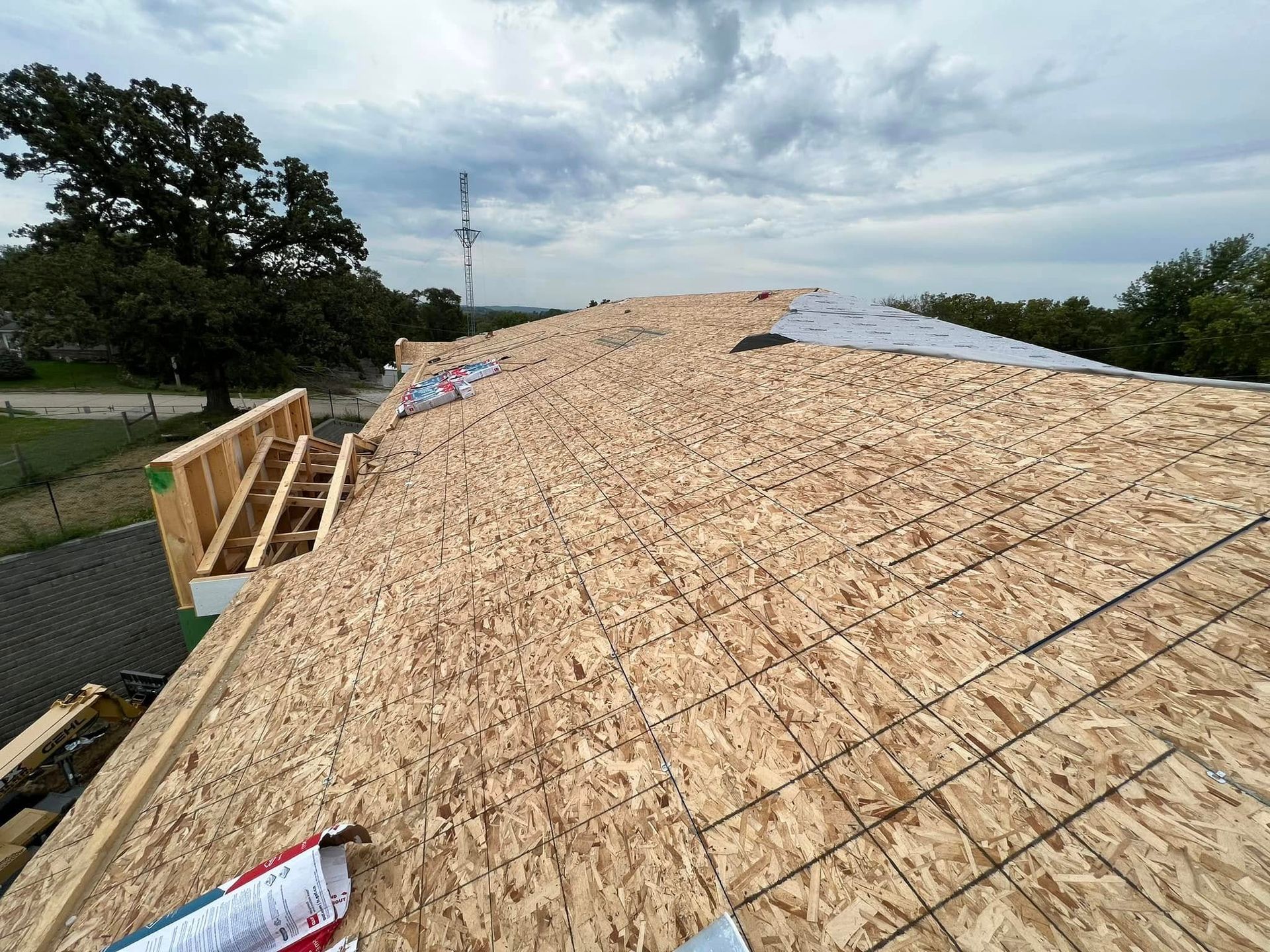 Roof under construction with plywood sheathing and cloudy sky overhead
