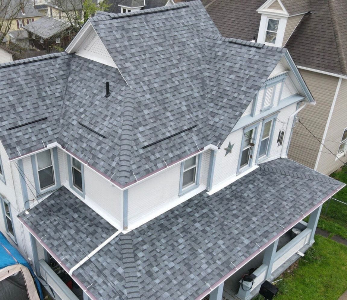 Aerial view of a gray-shingled house with white trim and a covered front porch