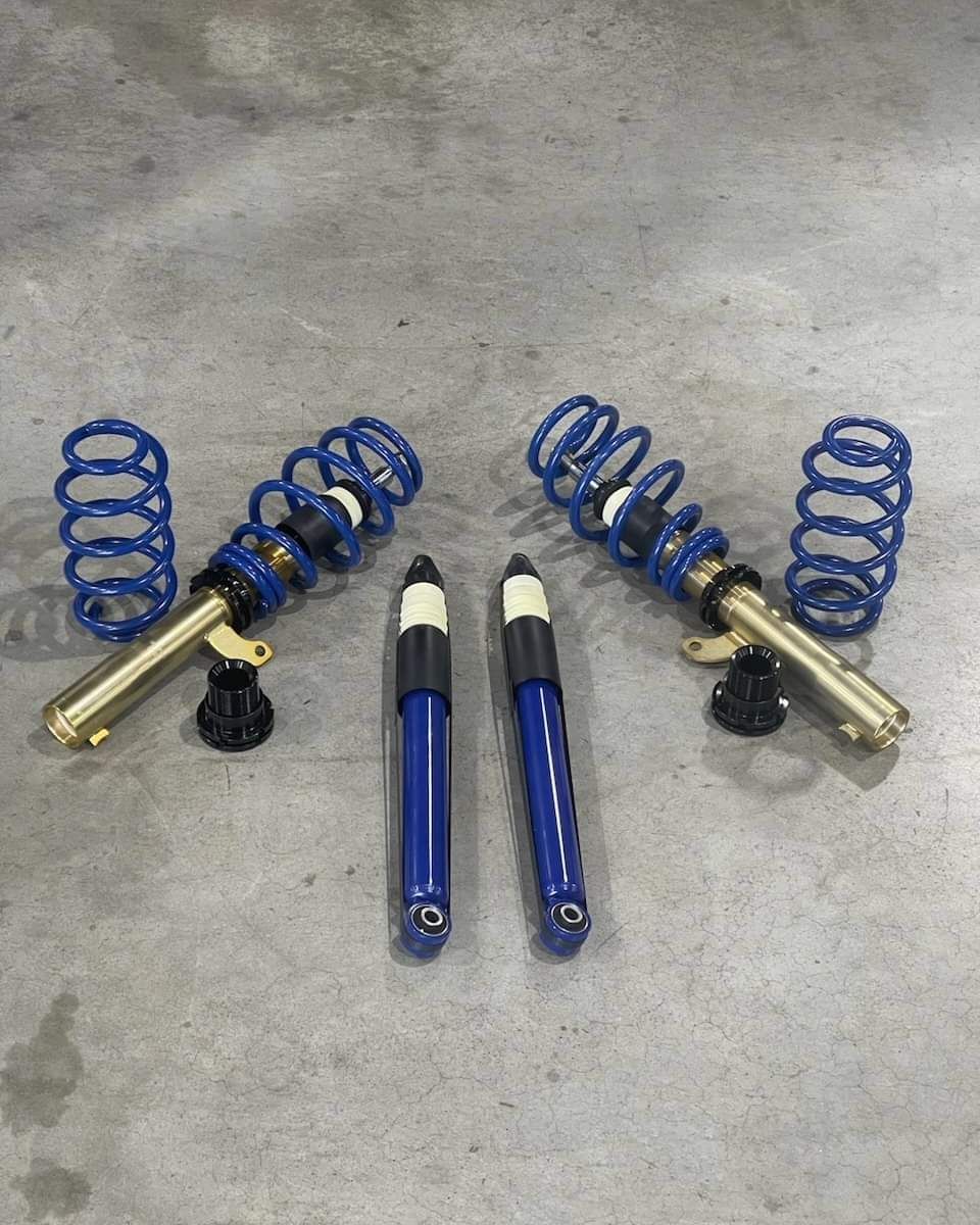 Blue and gold car suspension kit laid out on a gray surface.