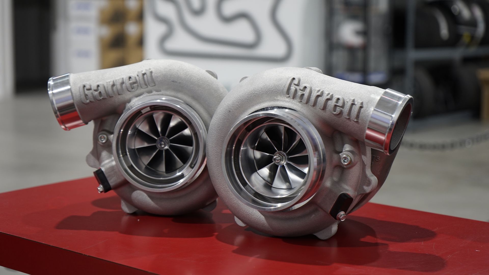 Two Garrett turbochargers on a red surface, close-up with a blurred background.