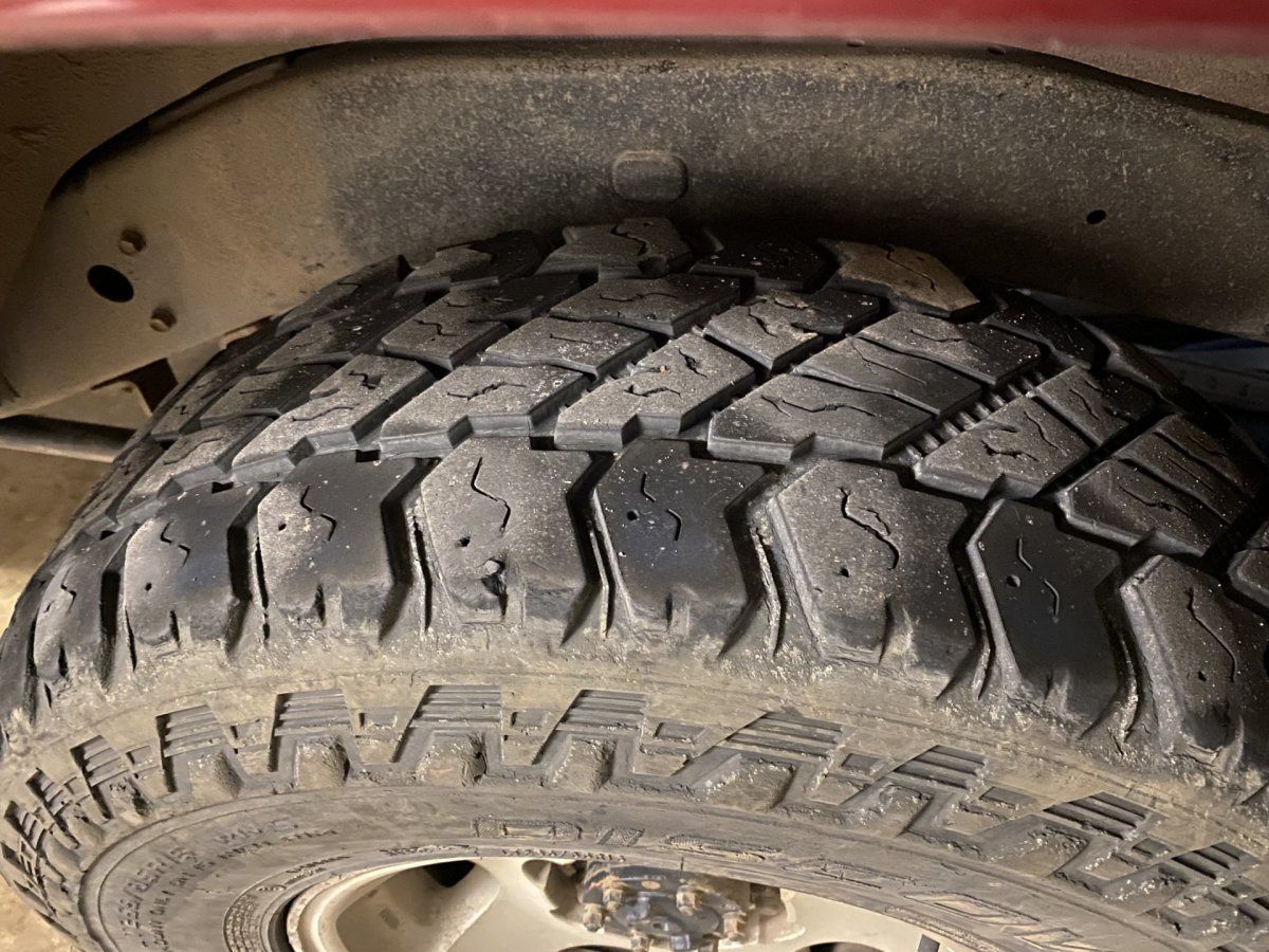 Close-up of a used tire on a vehicle, showing tread wear and the wheel well.