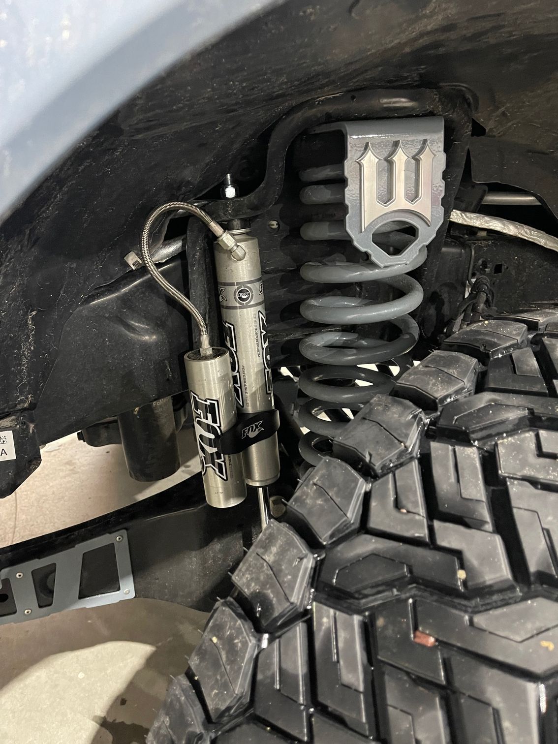 Off-road vehicle suspension system: coil spring, shock absorber, and tire visible in wheel well.