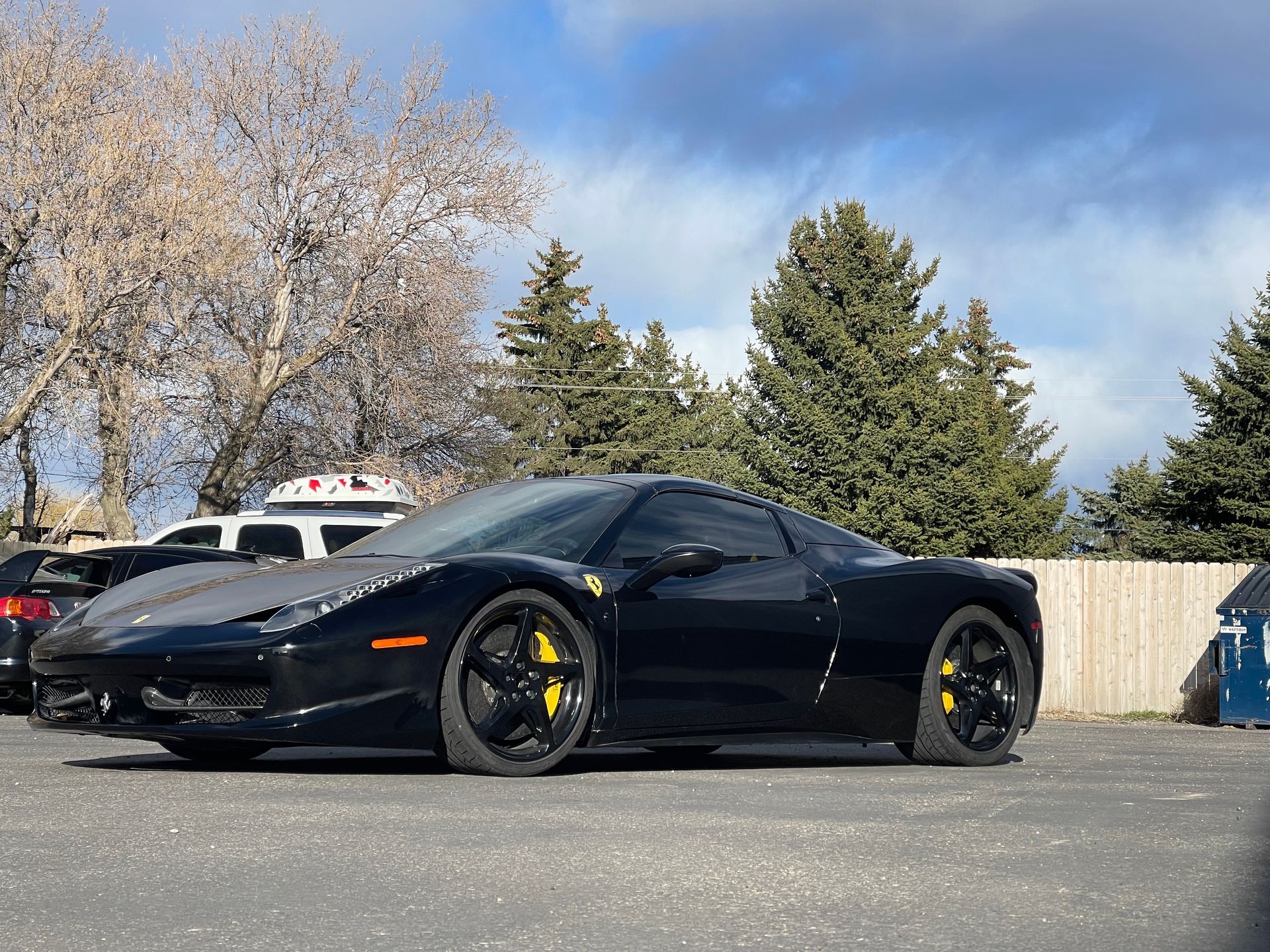 Black Ferrari sports car with yellow brake calipers parked on asphalt.