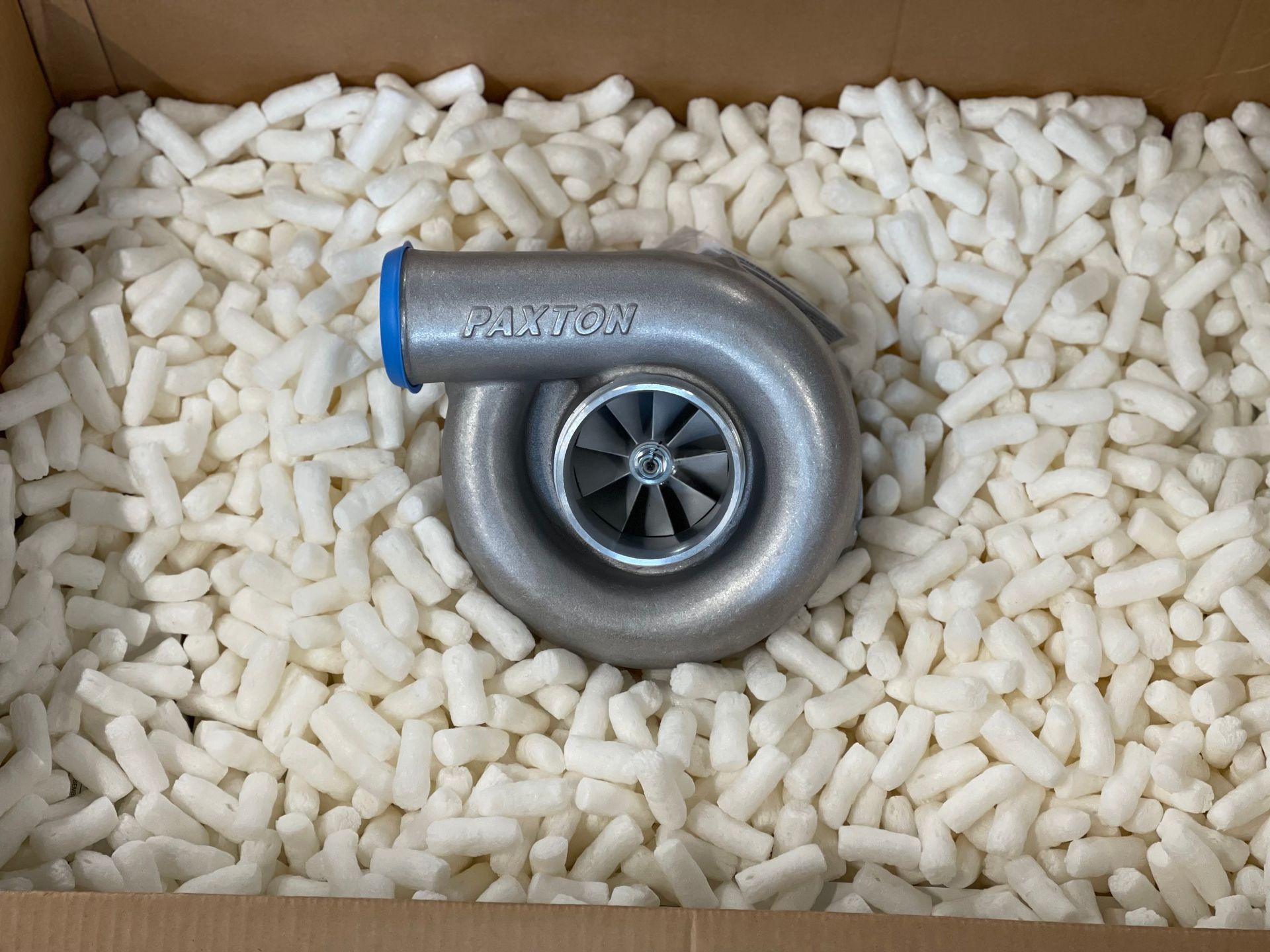 Turbocharger in a box, surrounded by white packing peanuts.