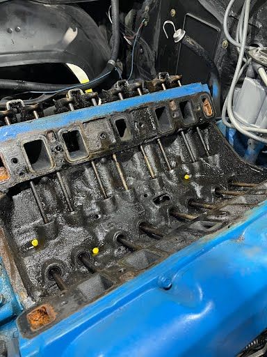Engine block, partially disassembled, with exposed components. Black engine components with traces of oil and blue engine mounting.