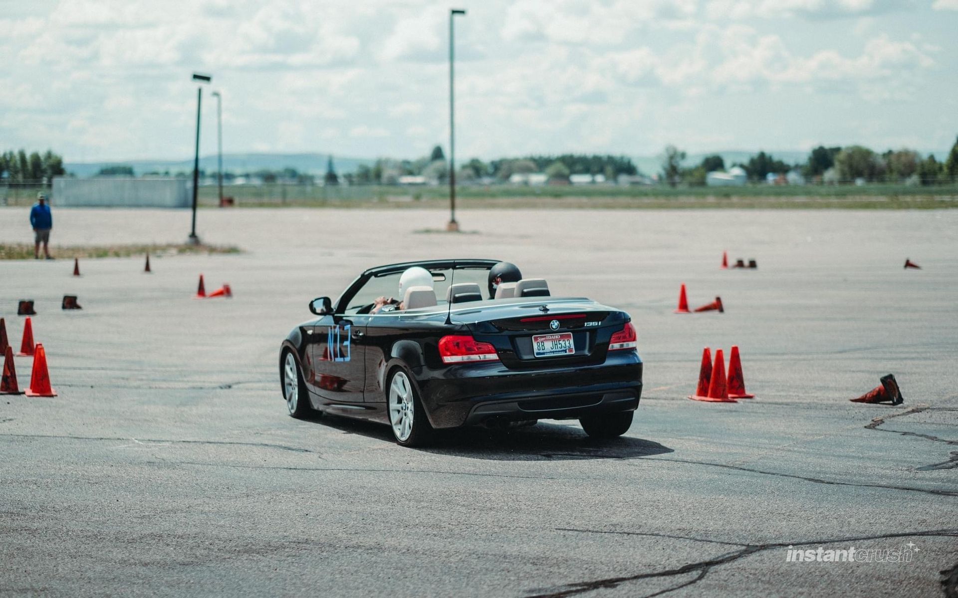 Black convertible car racing through an autocross course with orange cones on a paved track.