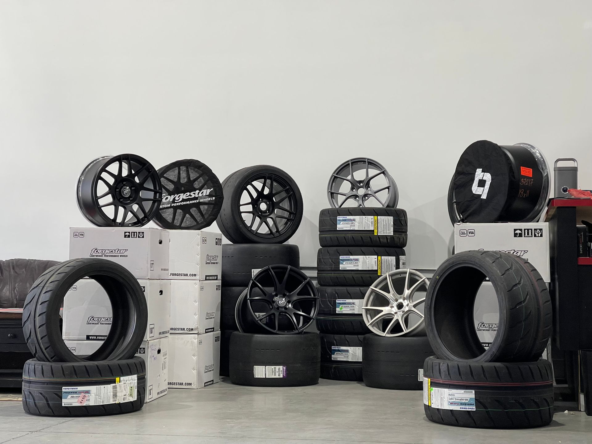 Tires and wheels for sale, stacked on boxes and the floor. Black and silver rims.
