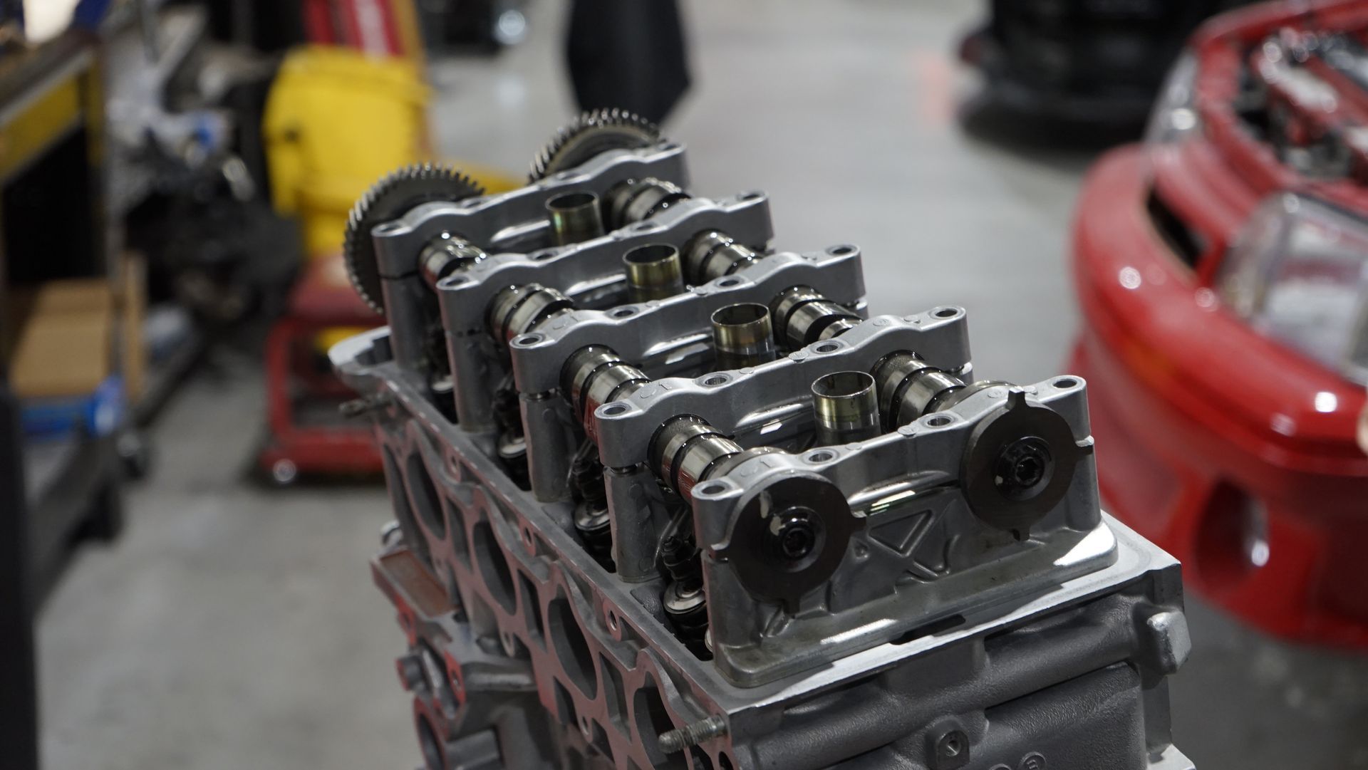 Engine cylinder head assembly with visible camshafts and gears.