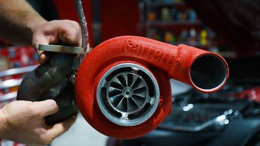 Person holding a red Garrett turbocharger and a gray exhaust housing.