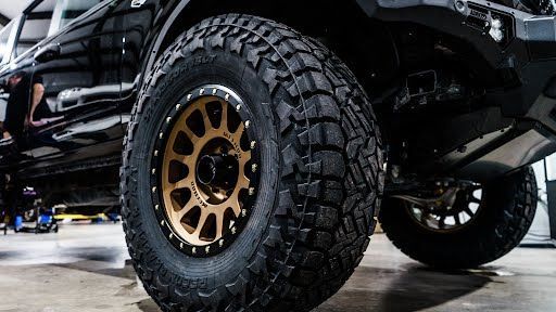 Black truck tire with gold rim.
