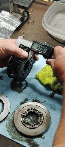 A person measures a metal part with digital calipers. The reading is 3.96.