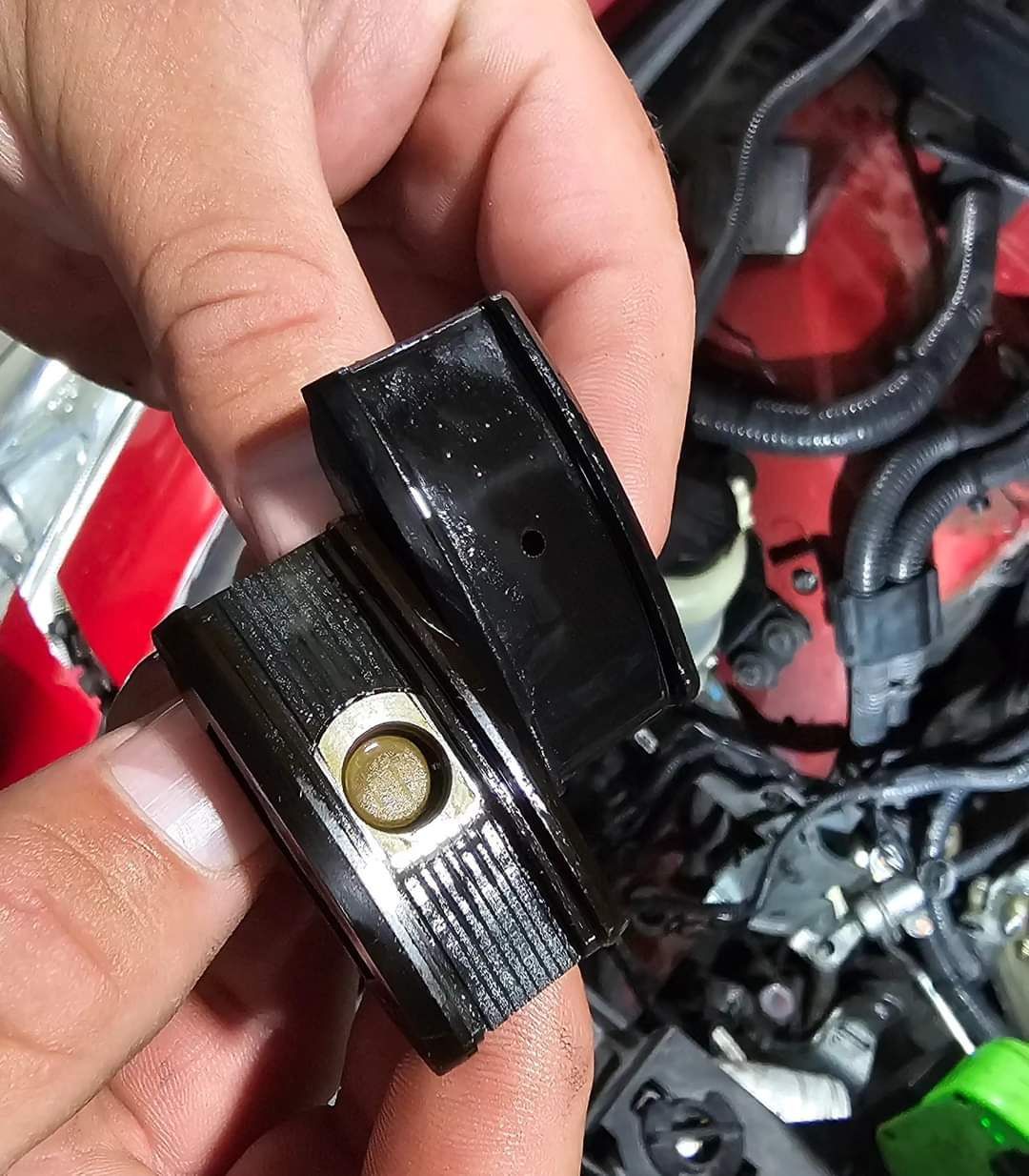 Hands holding two disassembled, oil-covered, black car parts with a round filter visible in one.