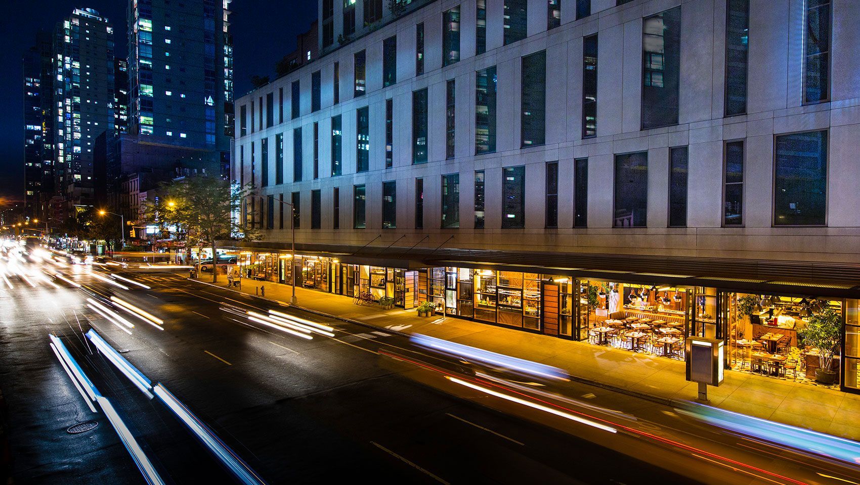 A long exposure photo of a city street at night with a large building in the background.