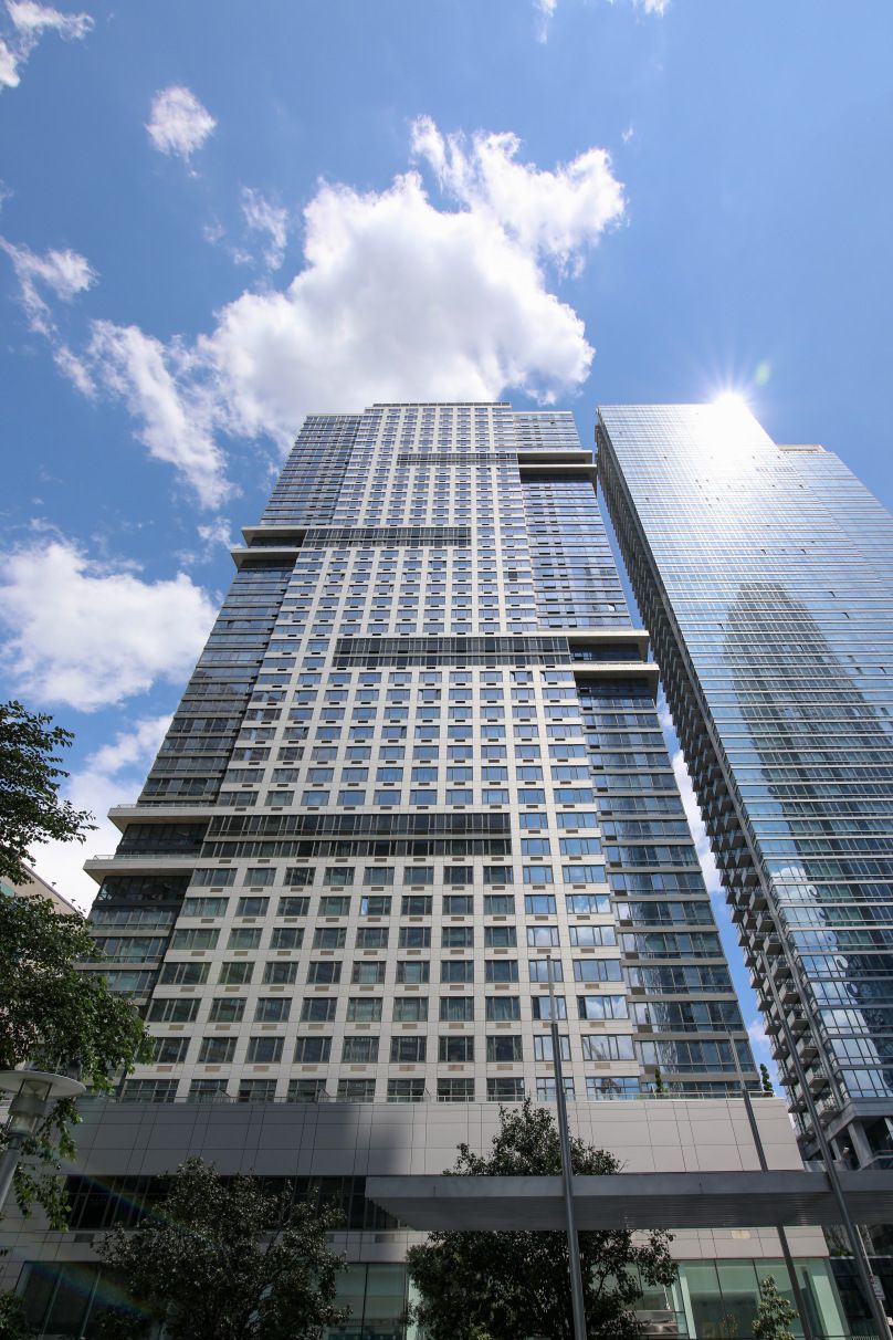 Looking up at a tall building with a blue sky and clouds in the background.