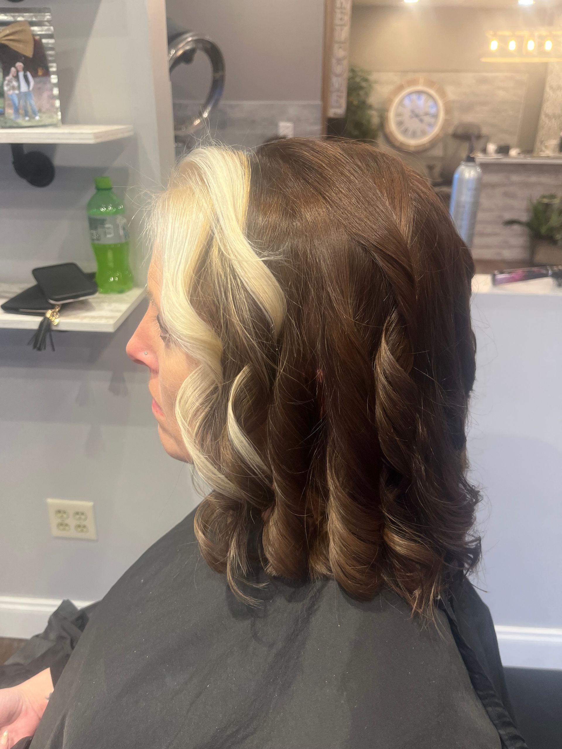 Woman with hair styled with half blonde and half brown waves in a salon.
