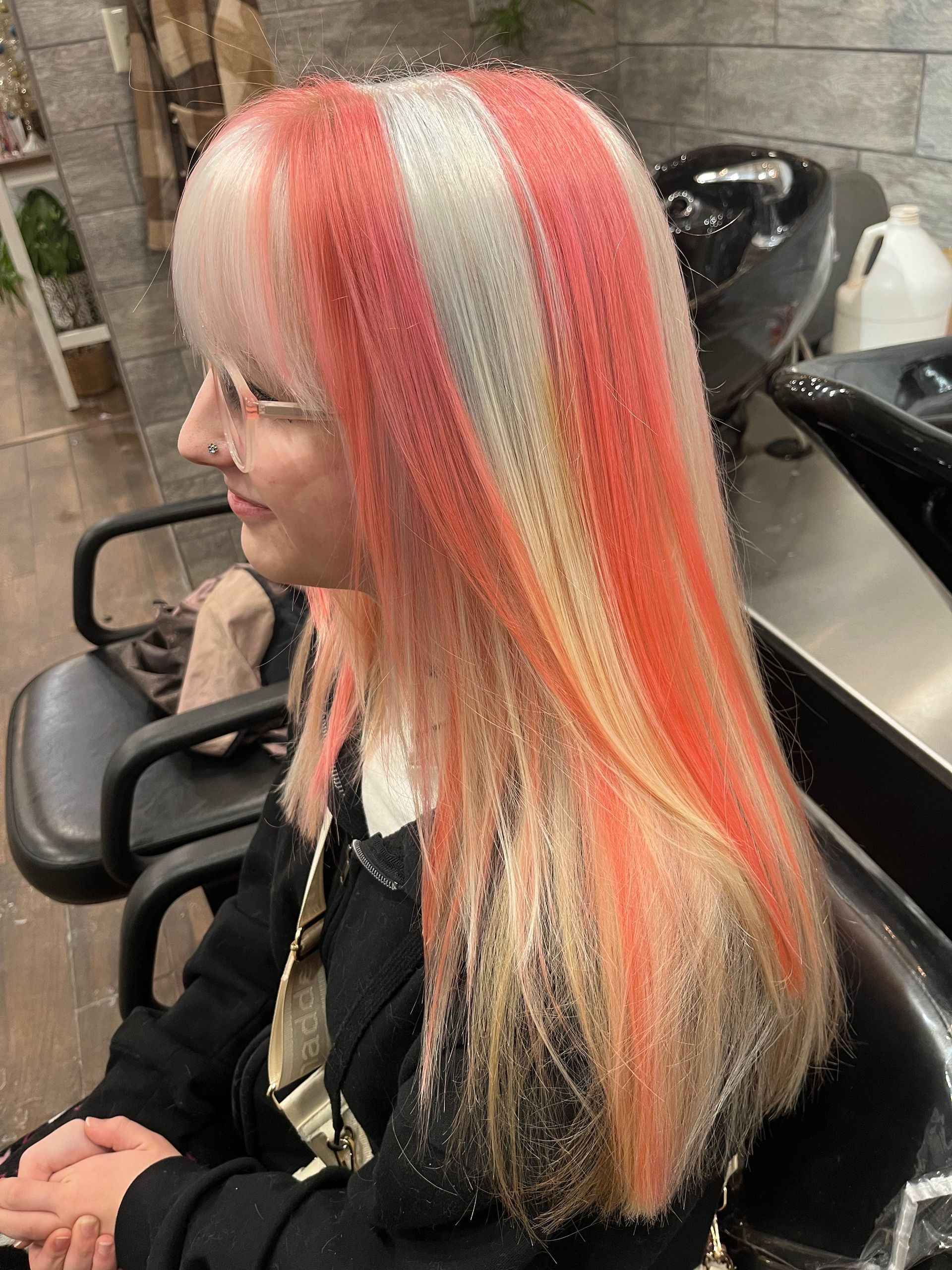 Woman with crimped hair in shades of red, white, and blonde, sitting in a salon chair.