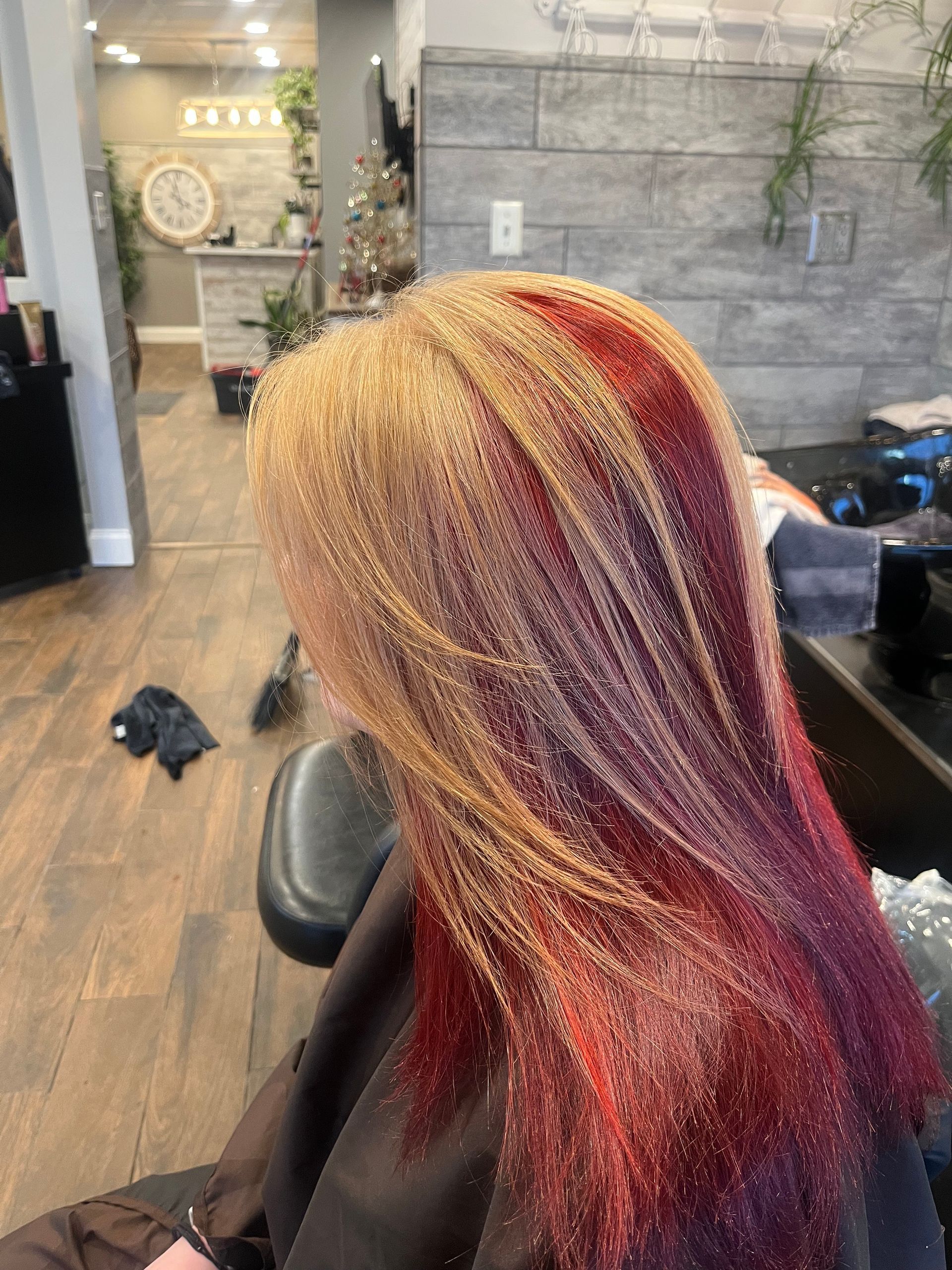 Woman with blonde hair and red highlights in a salon. 