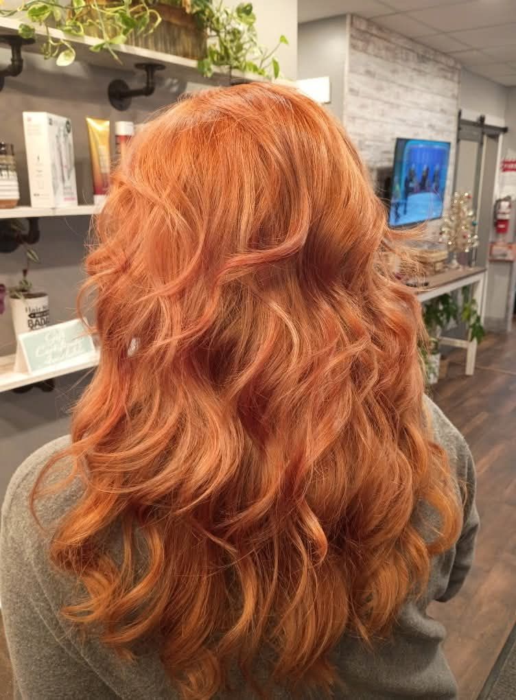 Woman with long, wavy orange hair, styled in a salon setting.