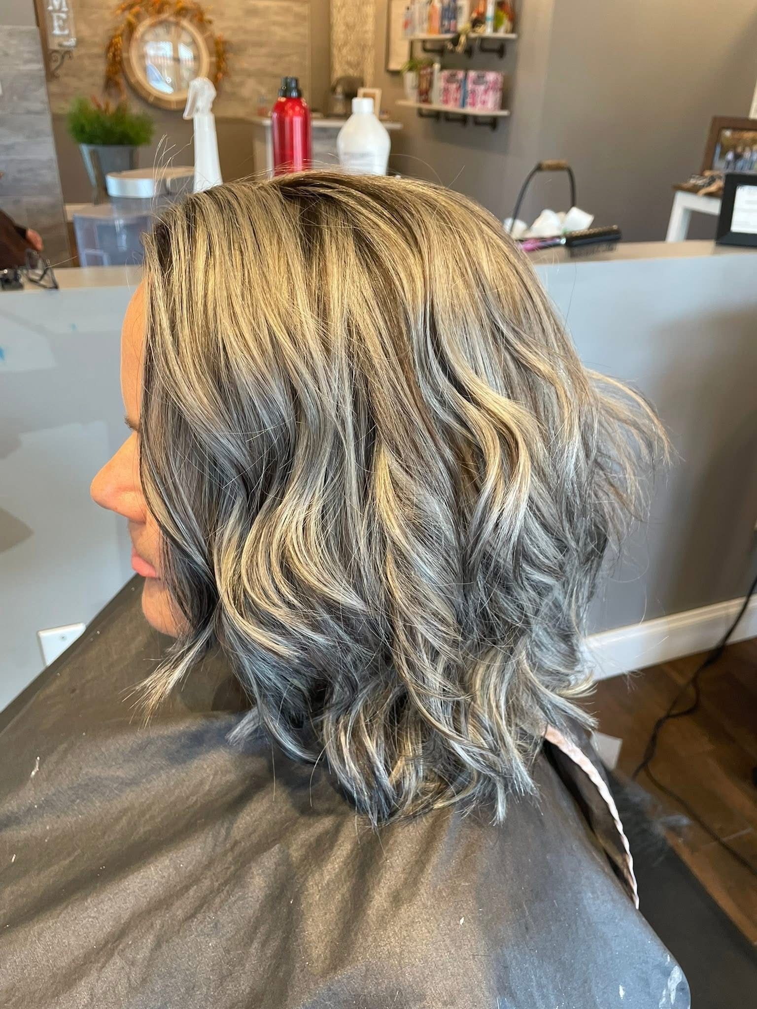 Woman with short wavy silver and blonde hair in a salon. 