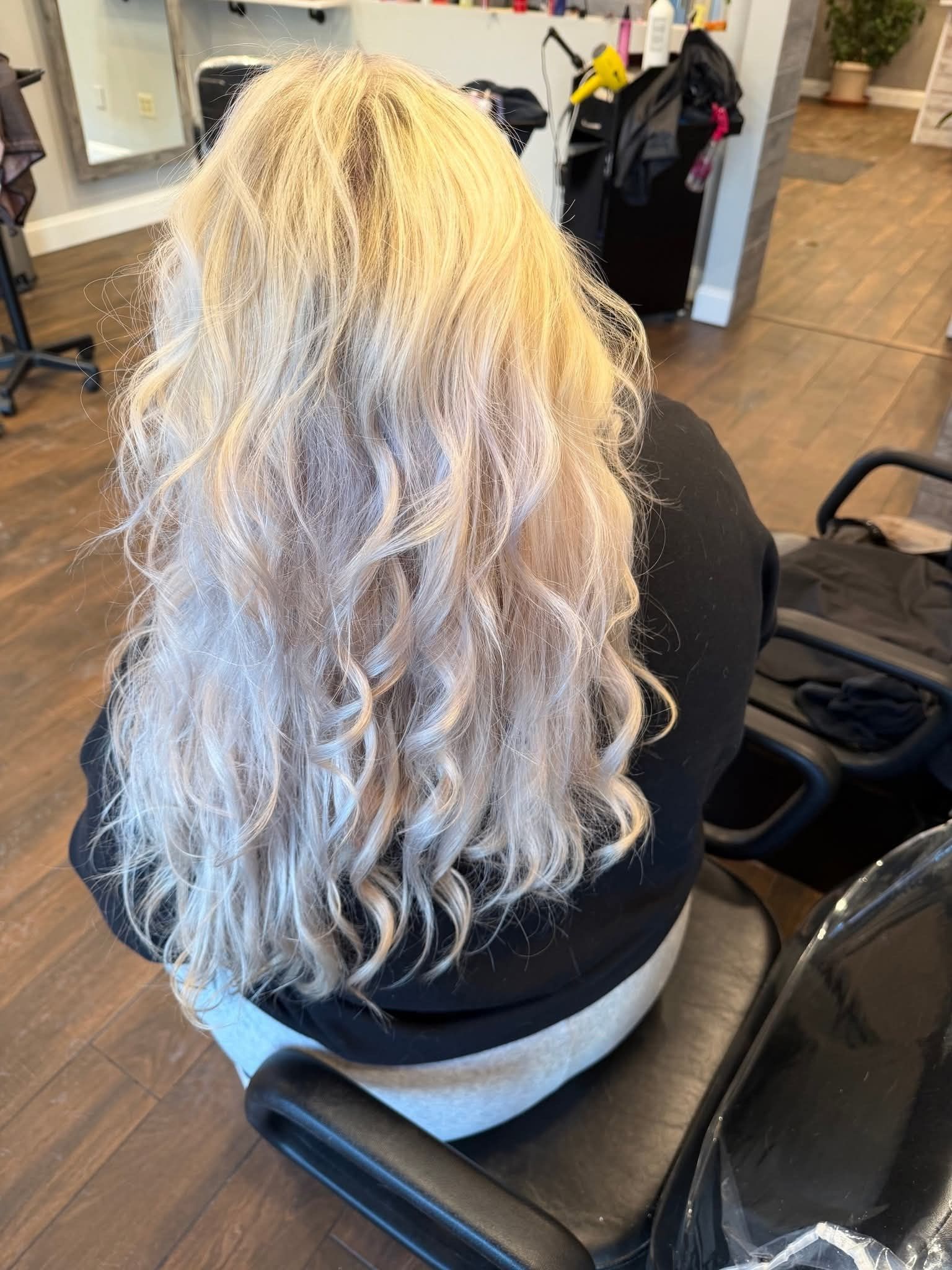 Blond wavy hair after a hair styling session in a salon, seated in a chair. 