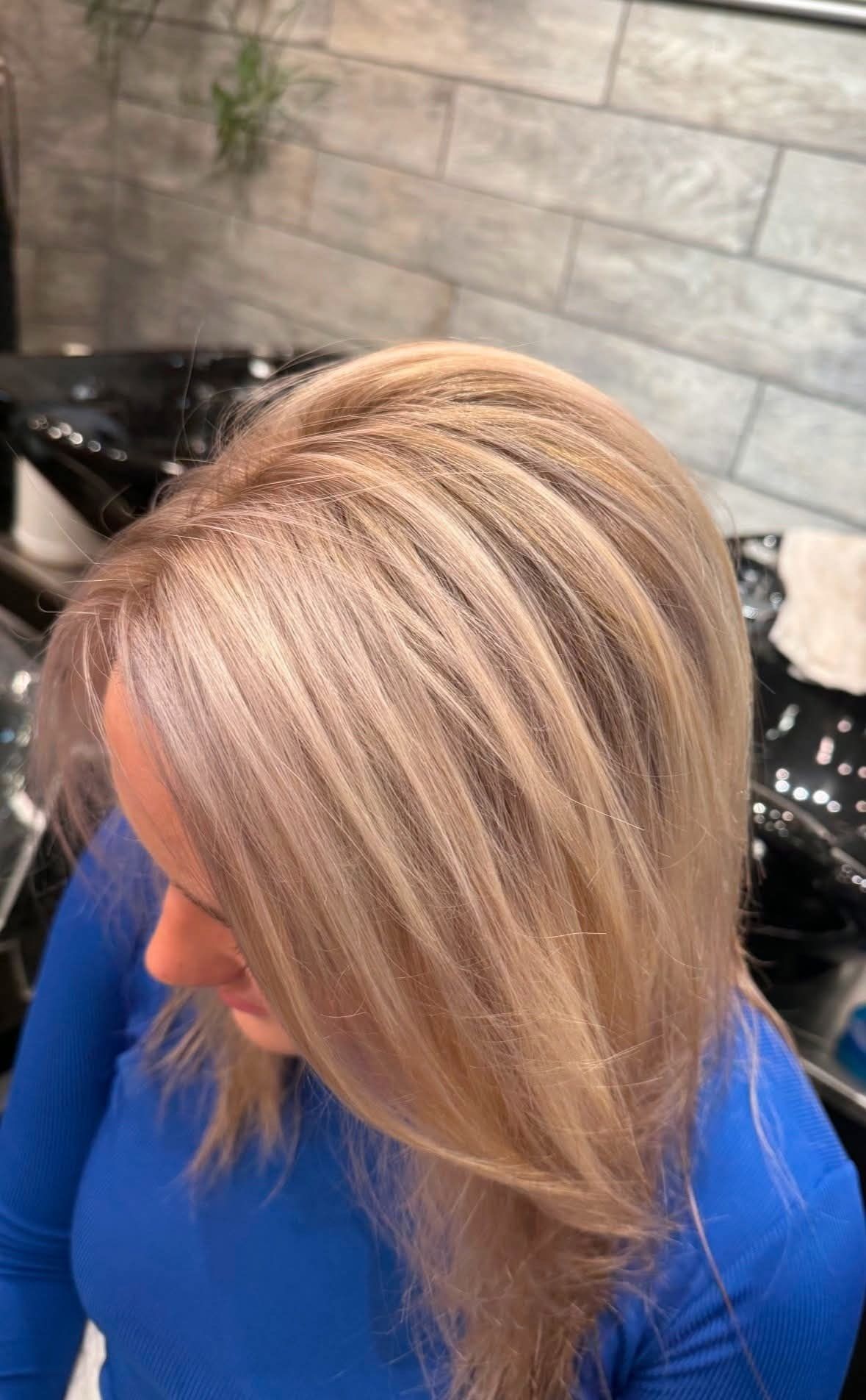 Woman with blonde hair, styled with highlights, wearing a blue shirt. 