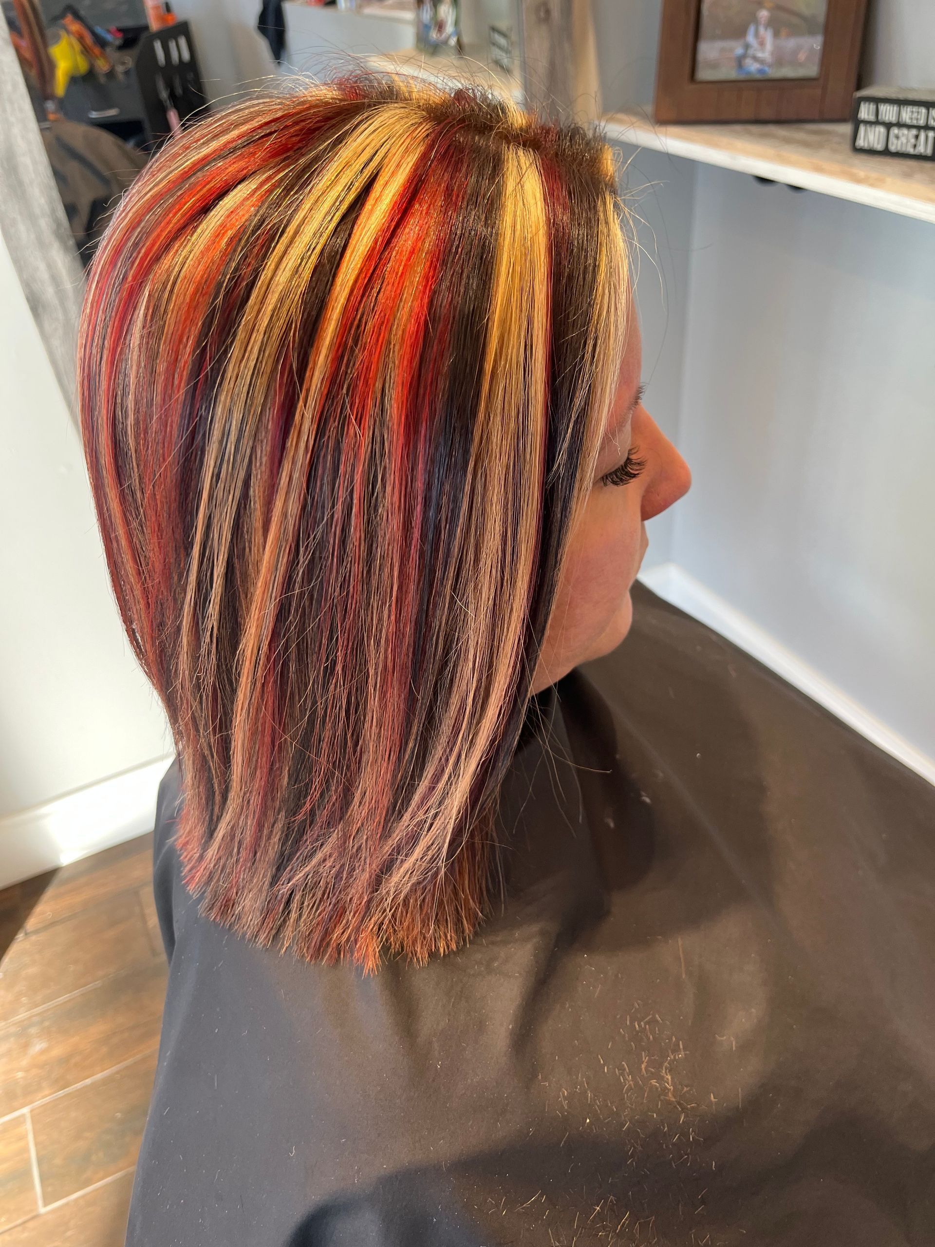 Woman with red, blonde, and brown highlights in a bob haircut at a salon. 