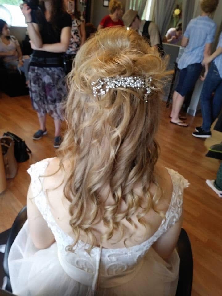 Bride with light brown curly hair, updo with jeweled hairpiece, wearing a white dress.