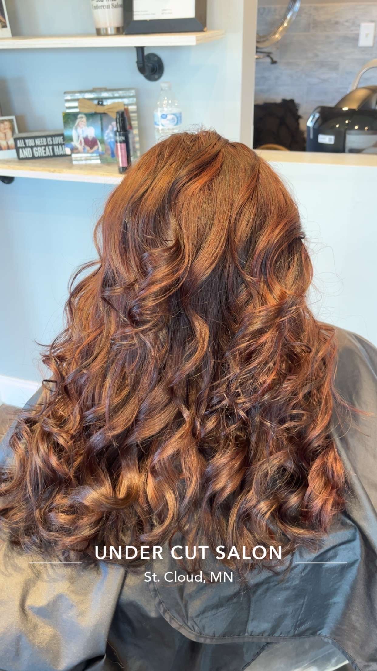 Long, wavy, reddish-brown hair styled after salon visit.  Under Cut Salon logo at bottom.