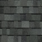 A pattern of overlapping, dark gray architectural roofing shingles with a textured, multi-tonal appearance.