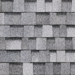 A close-up, top-down view of gray architectural asphalt roofing shingles arranged in an overlapping pattern.