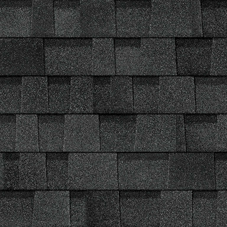A close-up of dark grey, architectural asphalt roof shingles layered in an overlapping, rectangular pattern.