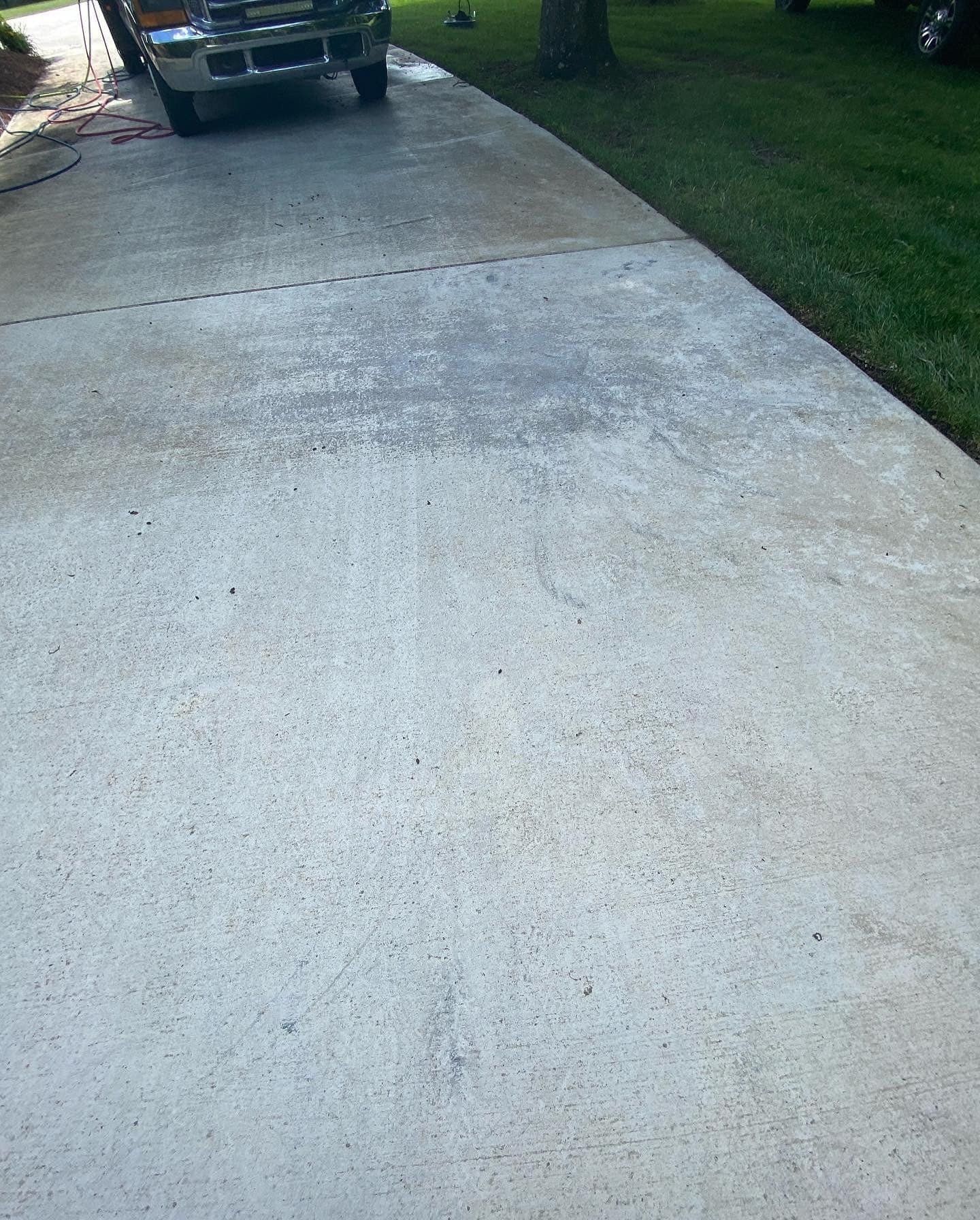 Driveway with a car parked on it, next to a green lawn.