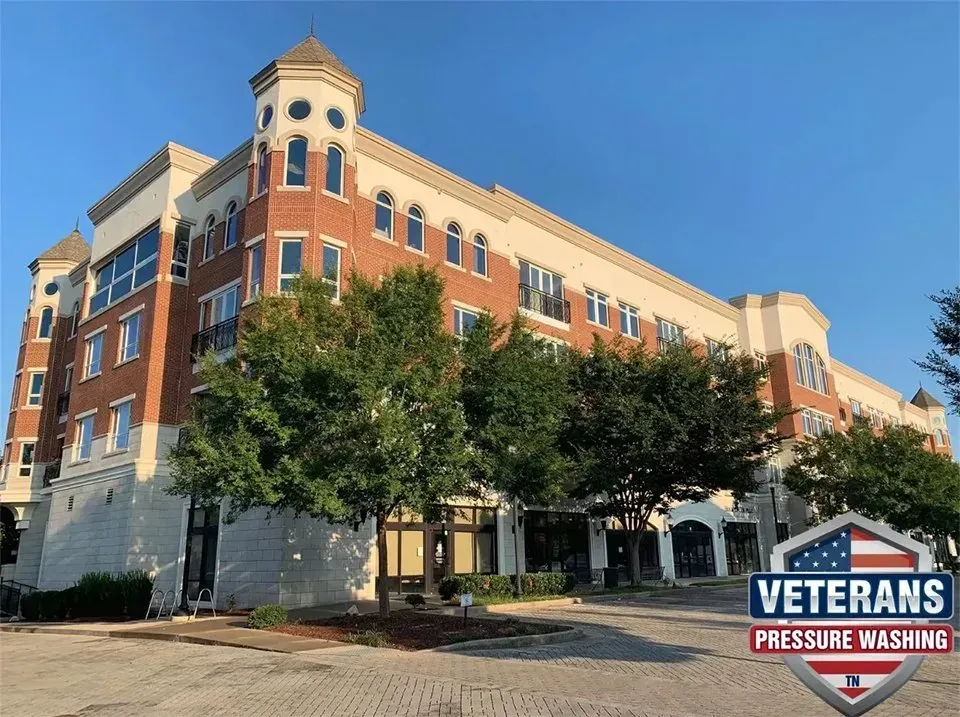 Multi-story building with brick and white accents; trees in front. Blue sky and 