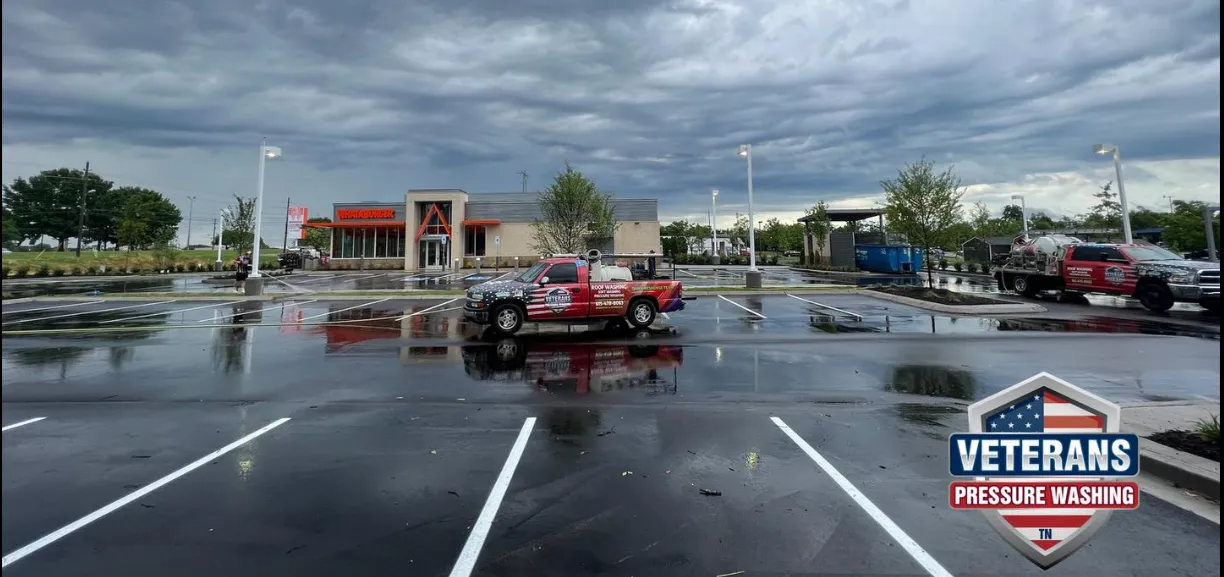 Wet parking lot with a red truck, storm clouds overhead. Store in the background.