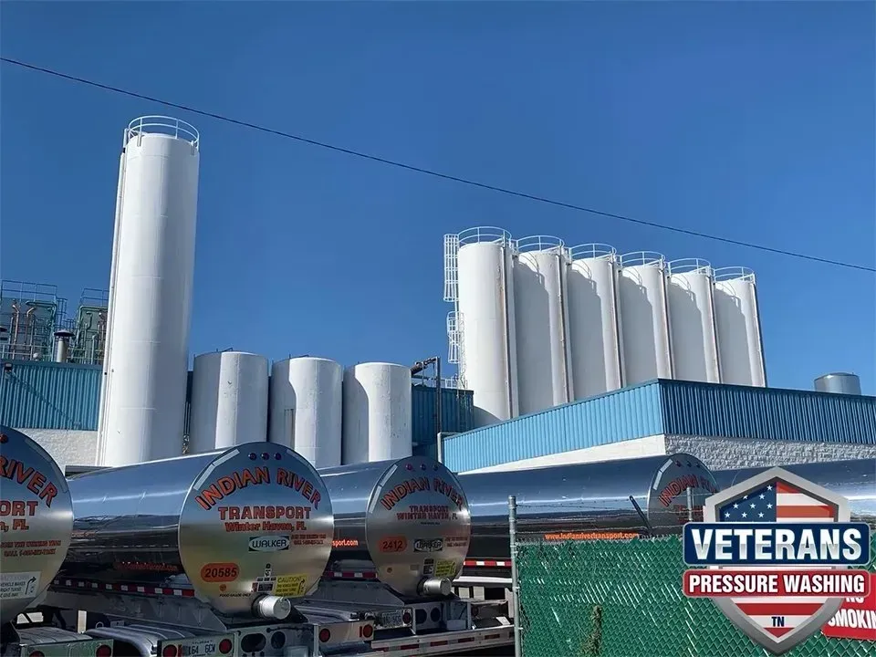 Dairy tanks and tanker trucks under a blue sky. 