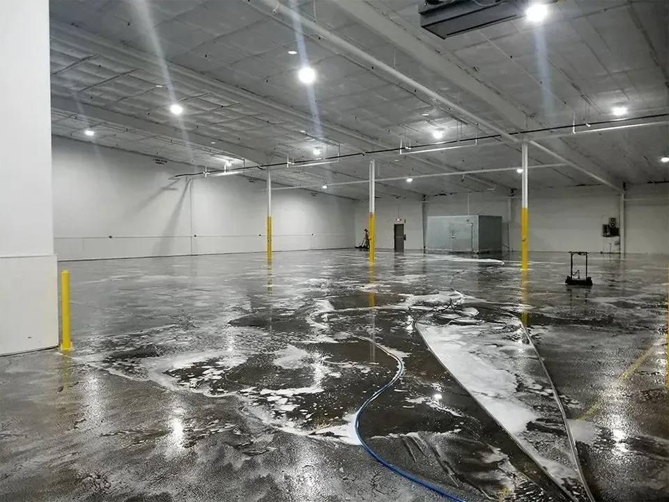 Large, empty warehouse floor being cleaned with soapy water.
