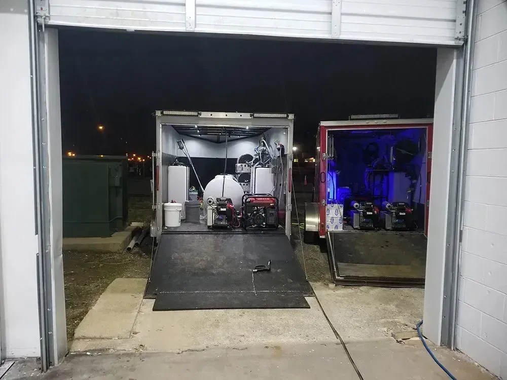 Two trailers open in a dark setting, one with red accents, both holding equipment.