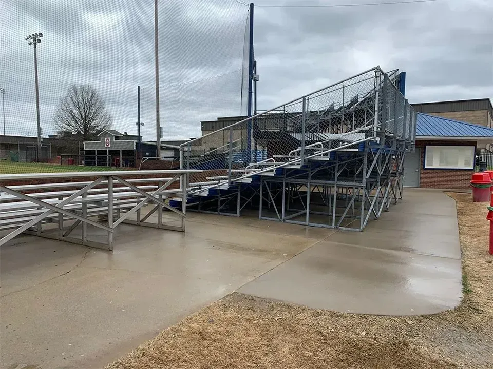 Bleachers at a baseball field on a wet day. Steel structure with blue seating.