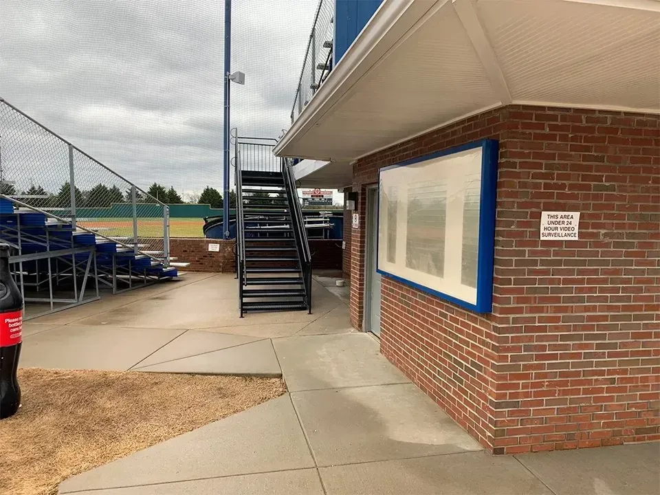 Baseball stadium exterior with brick building, stairs, and bleachers.