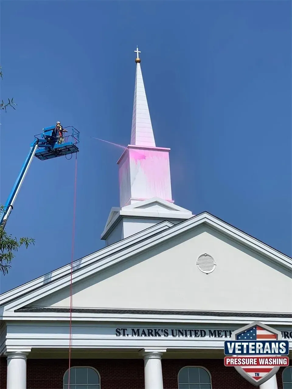 A person in a lift paints the steeple of St. Mark's United Methodist Church pink.