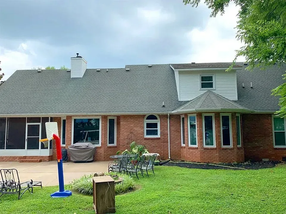 Red brick house with a basketball hoop in the backyard on an overcast day.