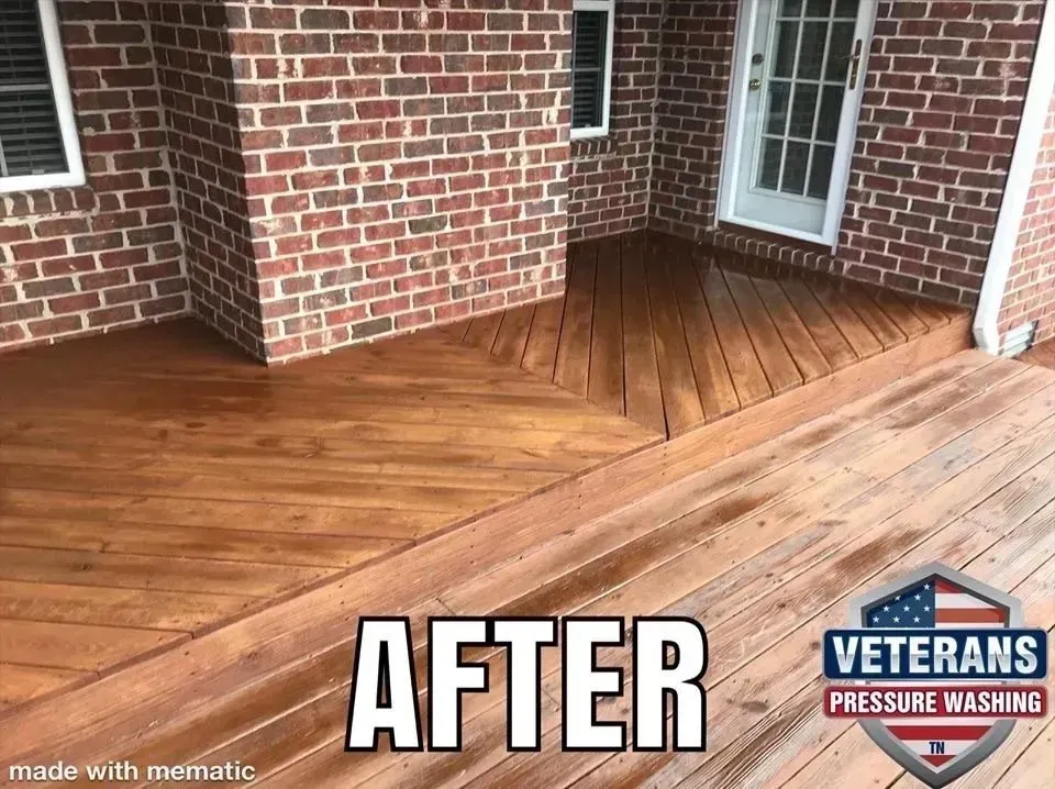 Cleaned wooden deck after pressure washing, with brick wall and white door.