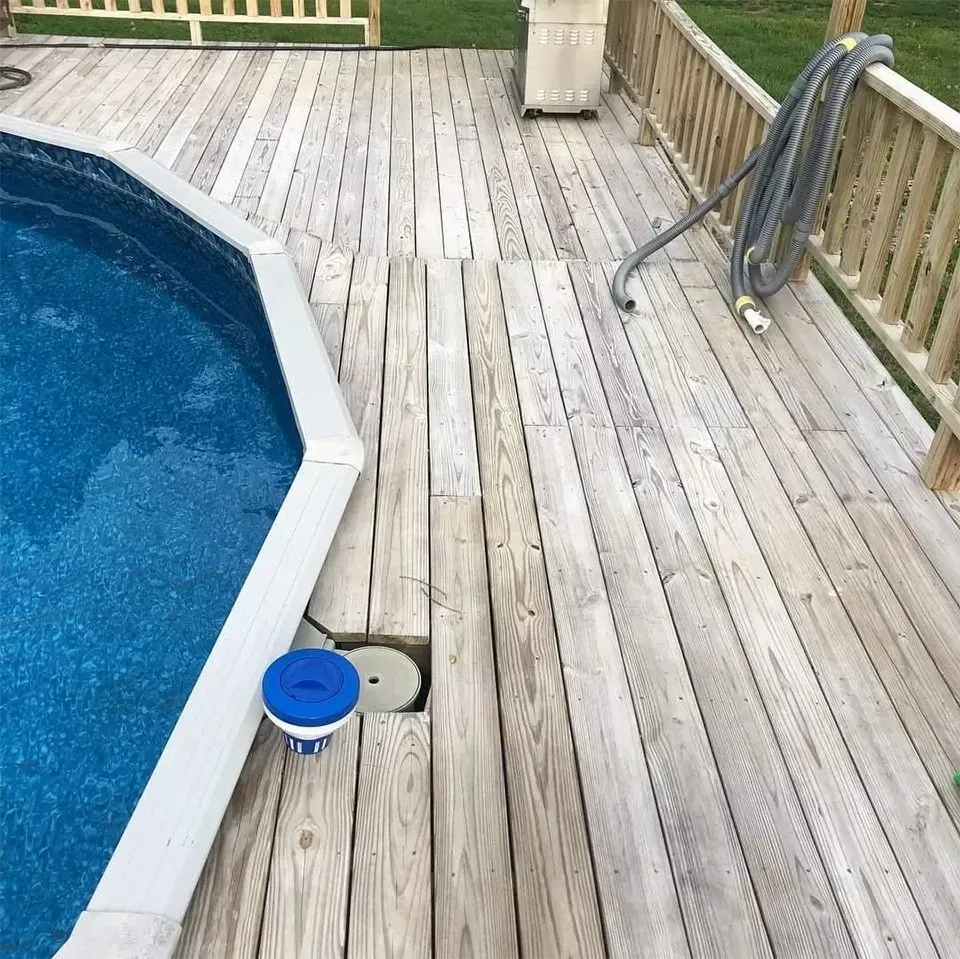 Wooden deck surrounds a blue pool. A blue bucket and hose are visible.